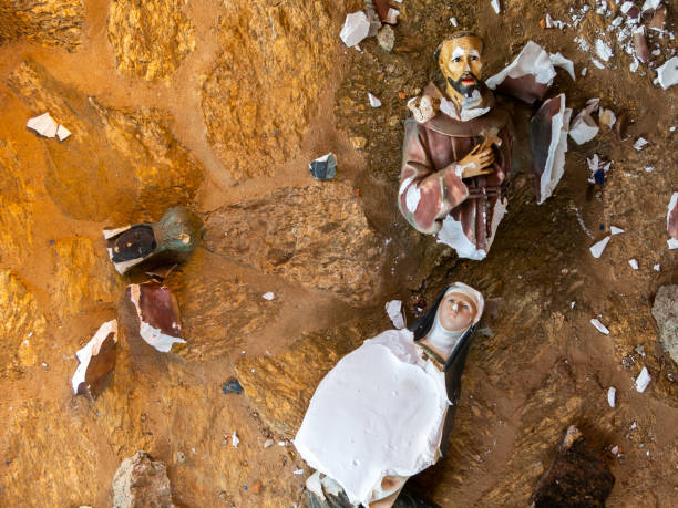 Broken vandalized plaster catholic plaster statues in the ground stock photo