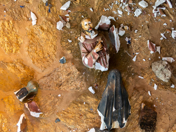 Broken vandalized plaster catholic plaster statues in the ground stock photo