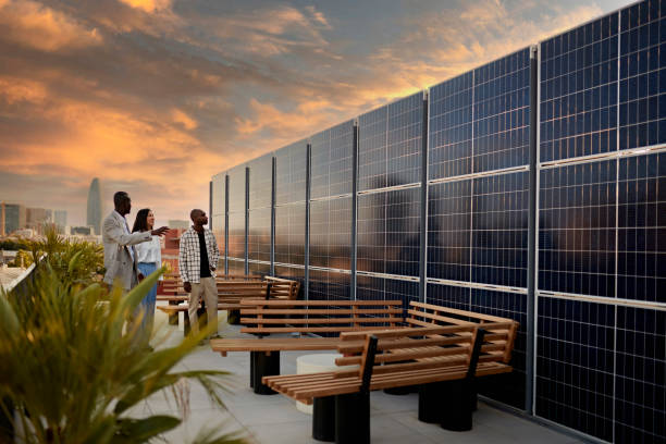 Broker and Prospective Buyers Admiring Solar Energy System Real estate agent and couple standing on rooftop of environmentally aware office building with dramatic sky and Barcelona cityscape in background at sunset. solar panel photos stock pictures, royalty-free photos & images