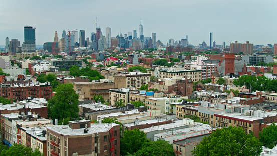 Aerial view of the Manhattan skyline from over rooftops in Crown Heights and Bedford-Stuyvesant in Brooklyn on a hazy day in summer.