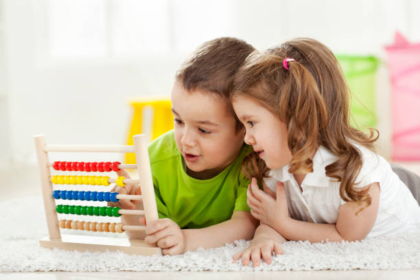 Brother and sister lyiing on the floor with abacus Brother and sister lying on the floor with abacus, having fun abacus stock pictures, royalty-free photos & images