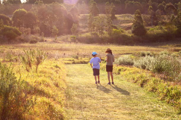 Brother and sister walking away in the countryside road stock photo