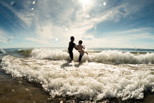 Brothers play in the ocean surf of Santa Barbara, California on Thanksgiving