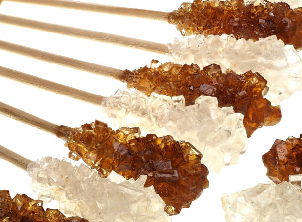 Brown and white candied sugar on wooden sticks stock photo