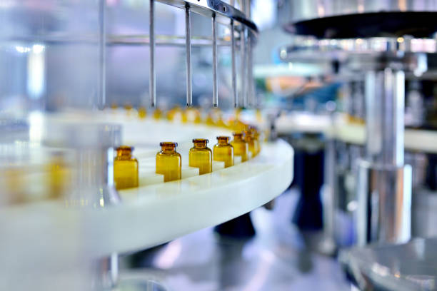 riempimento bottiglie di vetro marrone alla linea di produzione - farmaco foto e immagini stock