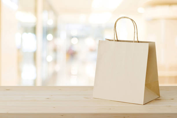 Brown paper shopping bag on wood table over blurred store background, business, template, retail, sale stock photo
