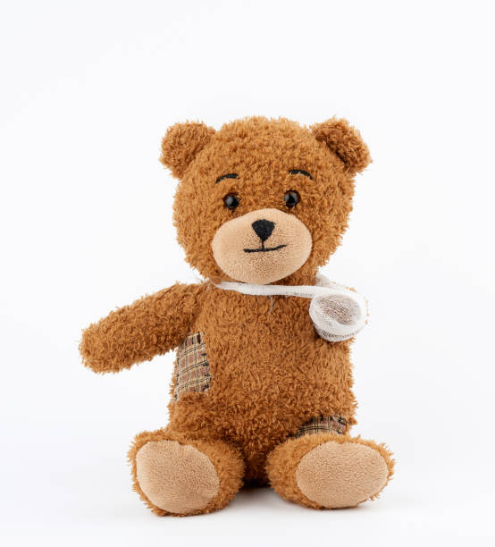 brown teddy bear with rewound white bandage paw on a white background brown teddy bear with rewound white bandage paw on a white background, pediatrics concept broken doll 1 stock pictures, royalty-free photos & images