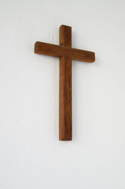 Brown wooden Christian Cross on white wall stock photo