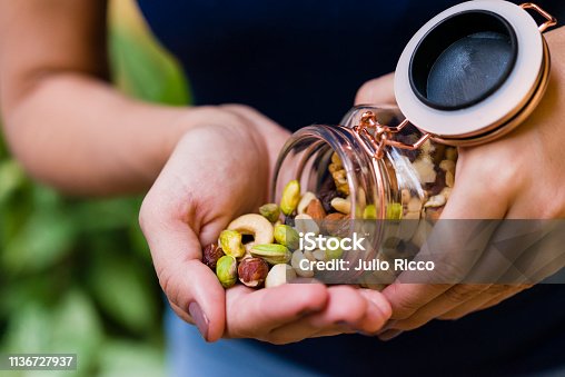 istock Brunette model hand holding glass hermetic pot with mix of nuts 1136727937