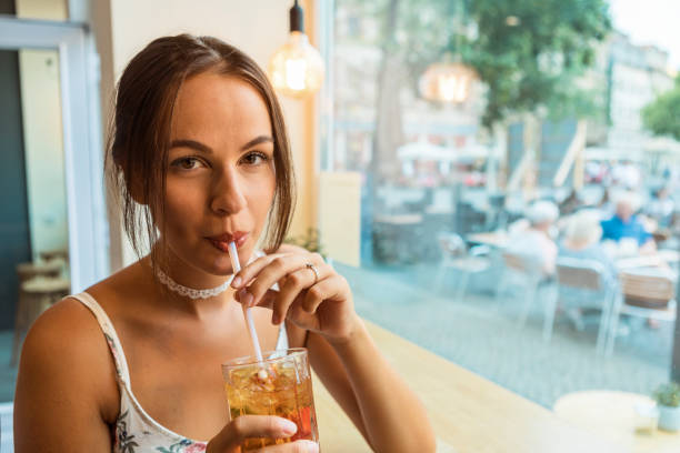 brunette woman having ice tea inside a café stock photo
