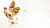 Bruschetta, toasted grilled Halloumi cheese and slices of avocado on white background top view with space for text. Healthy food. Long banner format.