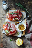 Bread with jamon, soft cheese, tomatoes, onion, pepper, rosemary and mustard