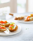 Bruschetta with salmon, curd cheese and cucumber on toast in high key style on white background.
