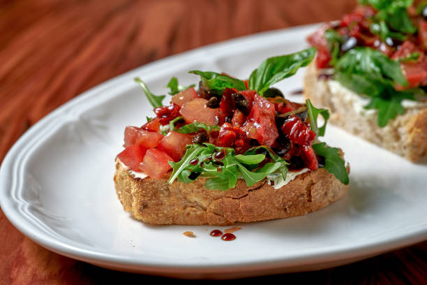 Bruschetta with sun-dried tomatoes and feta in a white plate on a wooden background stock photo