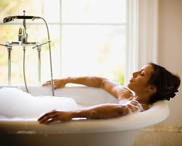 Bubble Bath A woman getting ready to take a bath. bathtub stock pictures, royalty-free photos & images