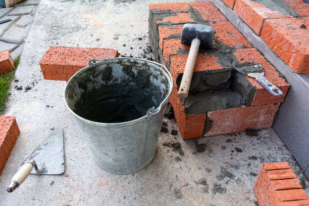 Bucket with a solute, trowel, rubber mallet and clay bricks stock photo