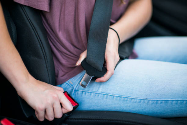 Buckling Up Close up of young female reaching over to put on a seat belt, practicing good safety habits. seat belt stock pictures, royalty-free photos & images