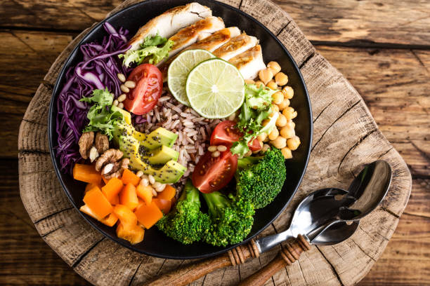Buddha bowl salad with chicken fillet, brown rice, avocado, pepper, tomato, broccoli, red cabbage, chickpea, fresh lettuce salad, pine nuts and walnuts. healthy food. balanced diet eating. Top view stock photo