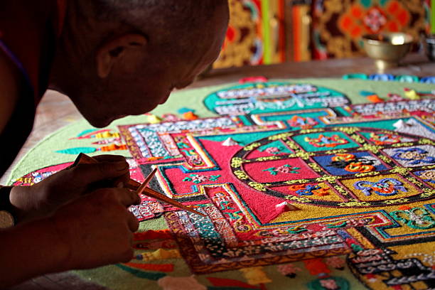 Buddhist monks making sand mandala Ladakh, Jammu & Kashmir, India - September 3, 2011: Buddhist monks making sand mandala in Diskit gompa (monastery) at Nubra Valley. This is a Tibetan tradition of creation and destruction of mandala made from colored sand. Mandala - is a spiritual and ritual symbol in Hinduism and Buddhism, representing the Universe. tibetan culture stock pictures, royalty-free photos & images