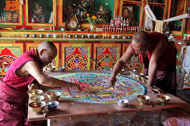 Buddhist monks making sand mandala Ladakh, Jammu & Kashmir, India - September 3, 2011: Buddhist monks making sand mandala in Diskit gompa (monastery) at Nubra Valley. This is a Tibetan tradition of creation and destruction of mandala made from colored sand. Mandala - is a spiritual and ritual symbol in Hinduism and Buddhism, representing the Universe. gompa stock pictures, royalty-free photos & images