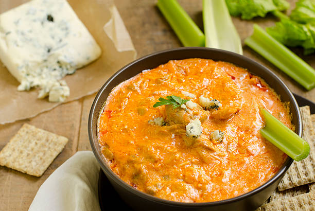 Buffalo Chicken Wing Dip Horizontal A bowl of Buffalo Chicken Wing Dip with blue cheese and celery in the background and crackers on the side.Similar Images: dipping sauce stock pictures, royalty-free photos & images