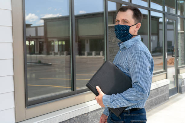 A builder on a finished construction site. A handsome engeneer wearing protective cotton mask during epidemic stock photo