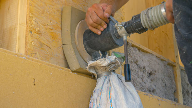 CLOSE UP: Builder uses a blower to insulate the wood wall with recycled paper. stock photo
