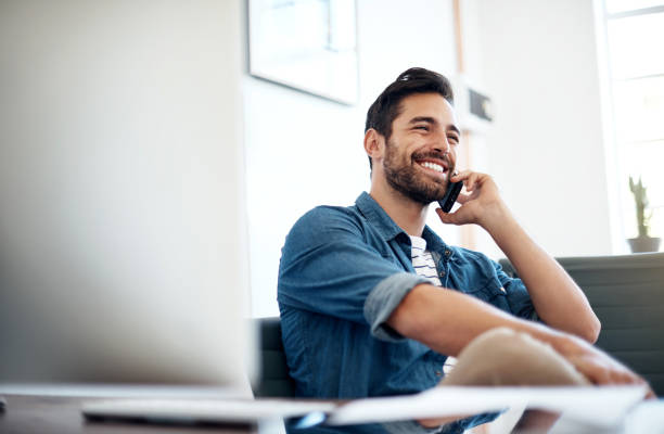 Building a trusting relationship with his clients Cropped shot of a young designer talking on a cellphone in an office handsome people stock pictures, royalty-free photos & images