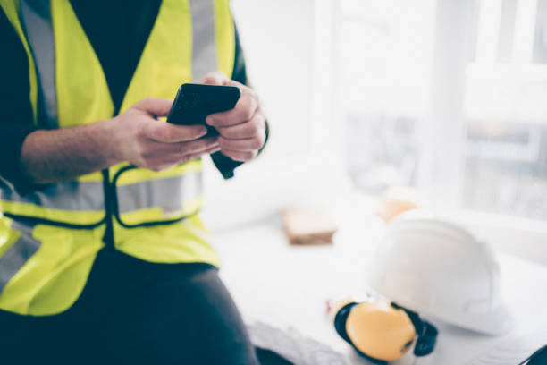 Building contractor using his phone to schedule the construction work stock photo