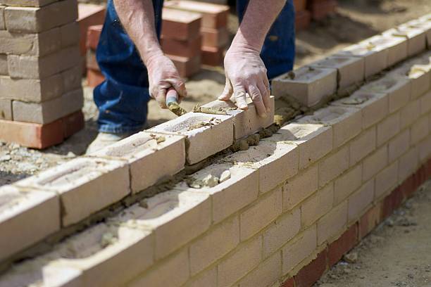 Building... The Hands of a skilled bricklayer as he builds the next course of bricks... bricklayer stock pictures, royalty-free photos & images