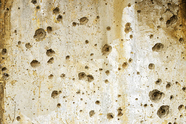 Bullet holes on a concrete wall stock photo