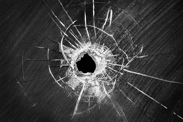 Bullet shot cracked hole on broken window glass stock photo
