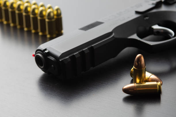 Bullets and black 9 mm semi-automatic pistol on black surface stock photo