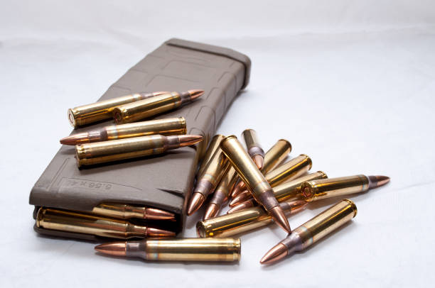 .223 bullets with a loaded magazine Several .223 caliber rounds and a loaded magazine on a white background ammunition stock pictures, royalty-free photos & images