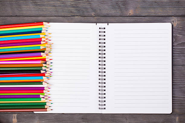 Bunch of color pencils and open notebook stock photo
