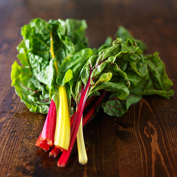 bunch of fresh rainbow chard bunch of fresh rainbow chard on wooden table in natural style light chard stock pictures, royalty-free photos & images