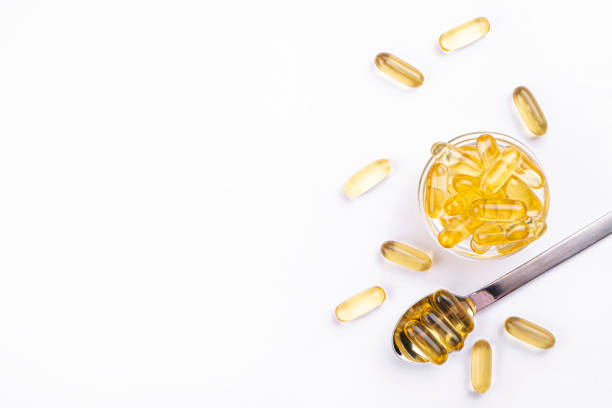 Bunch of healthy nutritious food supplements in a form of gel pills. Pile of omega 3 fish liver oil capsules in spoon. Big golden translucent pills on isolated background. Healthy every day fatty acids nutritional supplement. Top view, flat lay, copy space, close up fish oil stock pictures, royalty-free photos & images