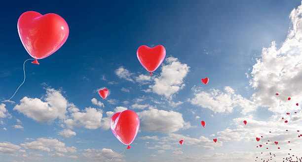 Bunch of heart shaped balloons appearing from horizon stock photo