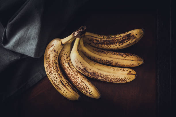 Bunch of Spotty, Overripe Bananas On A Table stock photo