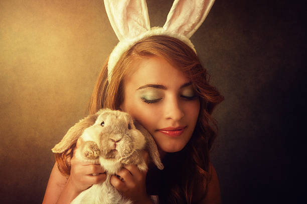зайчика девушка, держа кролика - bunny girl стоковые фото и изображения.