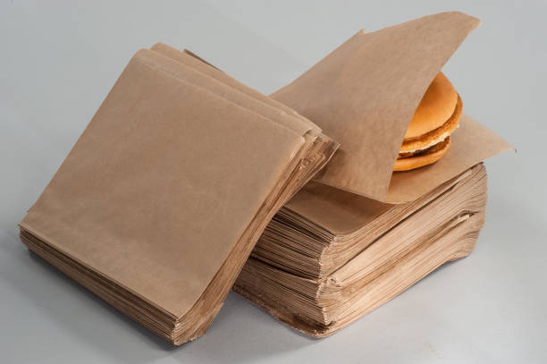 burger in brown paper packaging burger in brown paper packaging burger wrapped in paper stock pictures, royalty-free photos & images