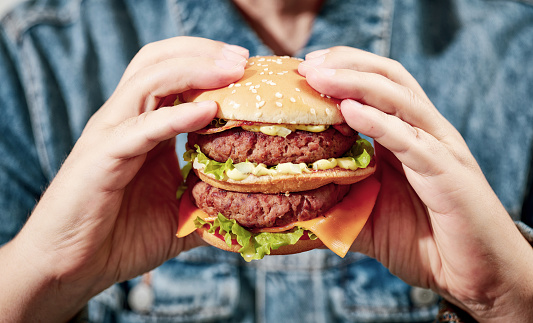 close up of burger in human hands, filtered image