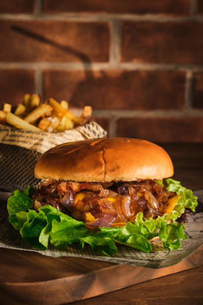 Burger with beef and caramelized onions on a wooden board. Cheeseburger with onion and beef. Juicy Delicious Homemade Burger. stock photo