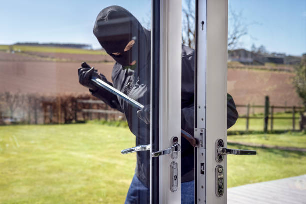 Burglar breaking into a house via a window with a crowbar stock photo