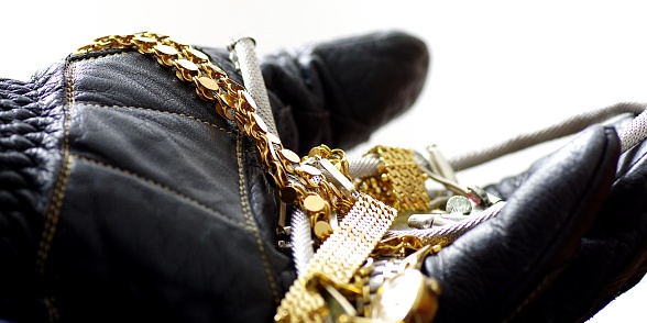 Hand of a burglar with glove and gold jewelry