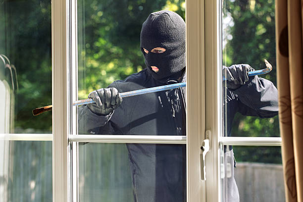 Burglary Burglar breaking into a house via a window with a crowbar burglary stock pictures, royalty-free photos & images