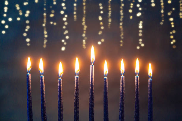 Burning blue candles on a Jewish menorah at Hanukkah with glittering bokeh string lights behind it Burning blue candles on a Jewish menorah at Hanukkah with glittering bokeh string lights behind it hanukkah stock pictures, royalty-free photos & images