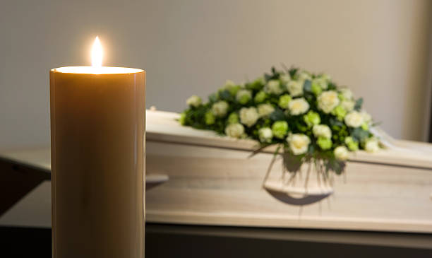 Burning candle in front of coffin A burning candle with a coffin and a flower arrangement on the background in a mortuary crematorium stock pictures, royalty-free photos & images