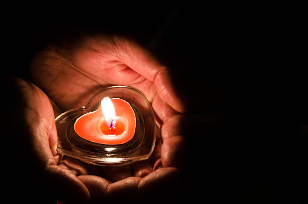 burning candle in hands stock photo