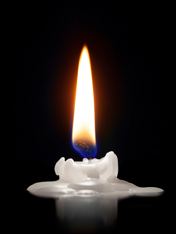 Candle glowing on a black background.